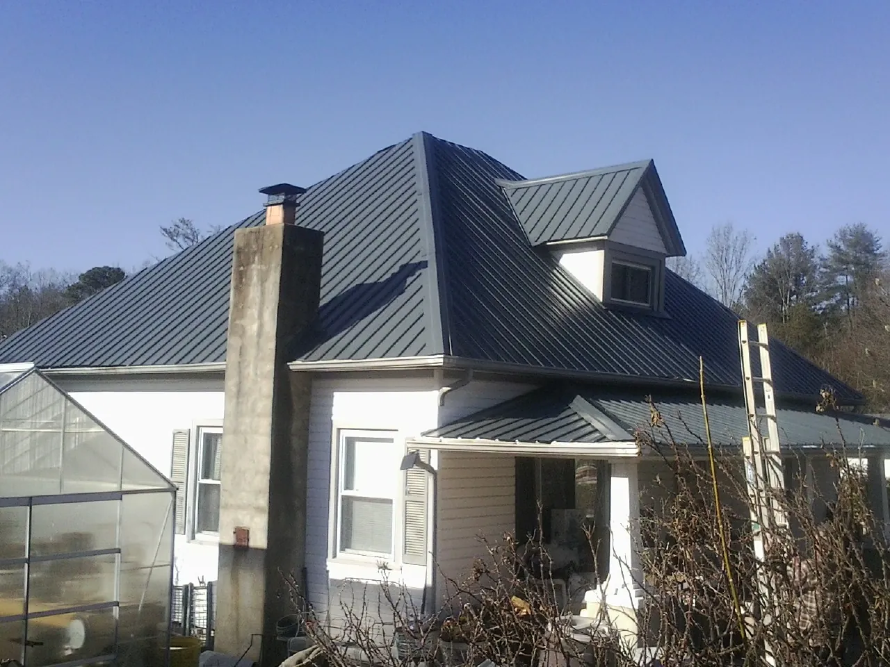 Dark blue standing seam metal roof on a white farmhouse with dormer — Slate & Tile Roof Repair by Roofing Brothers in Glen Hope