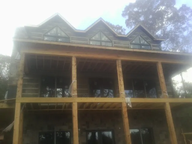 Dormers and porch framing on a large log home under construction — Roof Coating work by our crew in Glen Hope