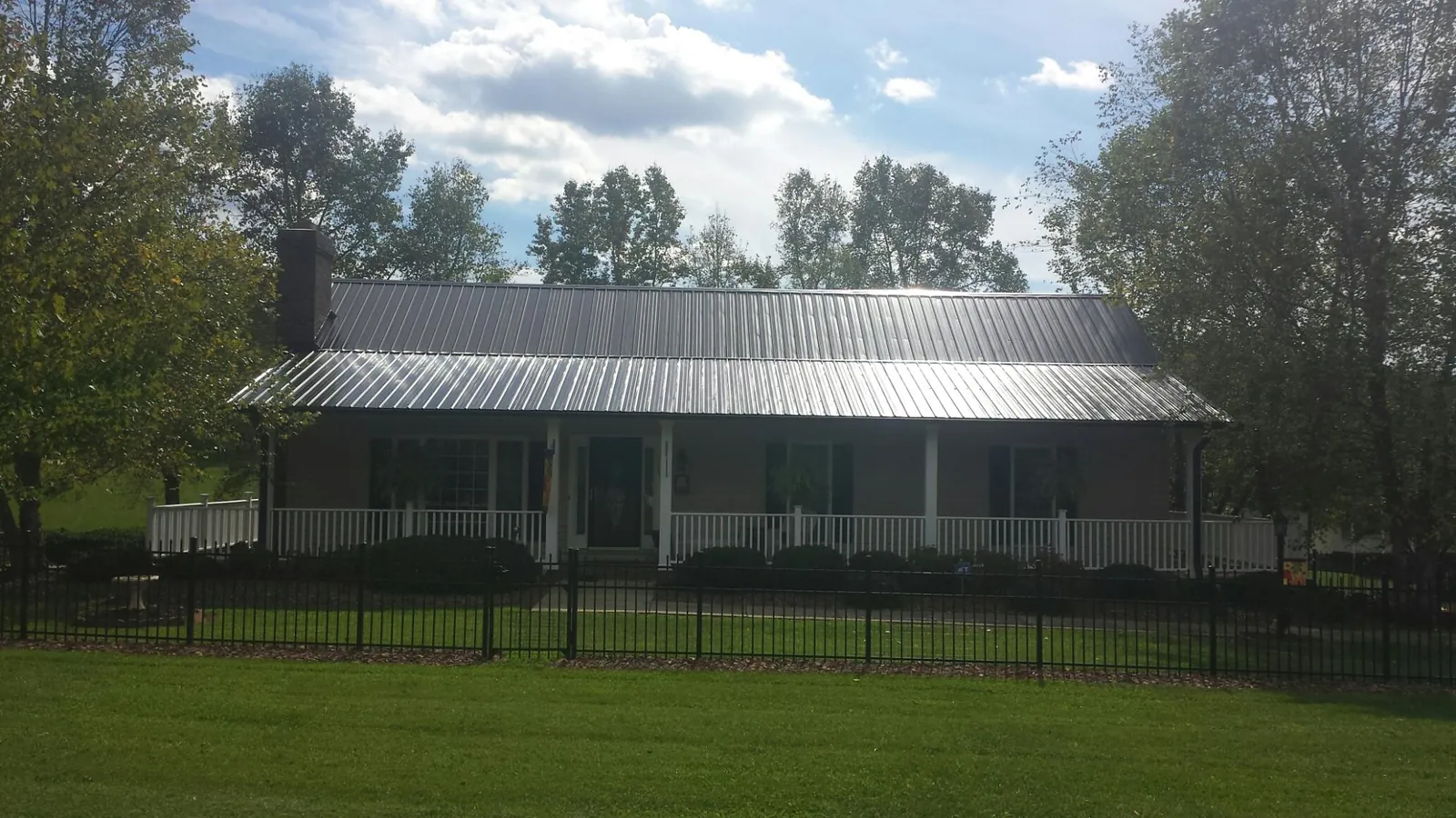 Gray metal roof on a brick ranch with a full width front porch — Gutter Guard Installation work by our crew in Glen Hope