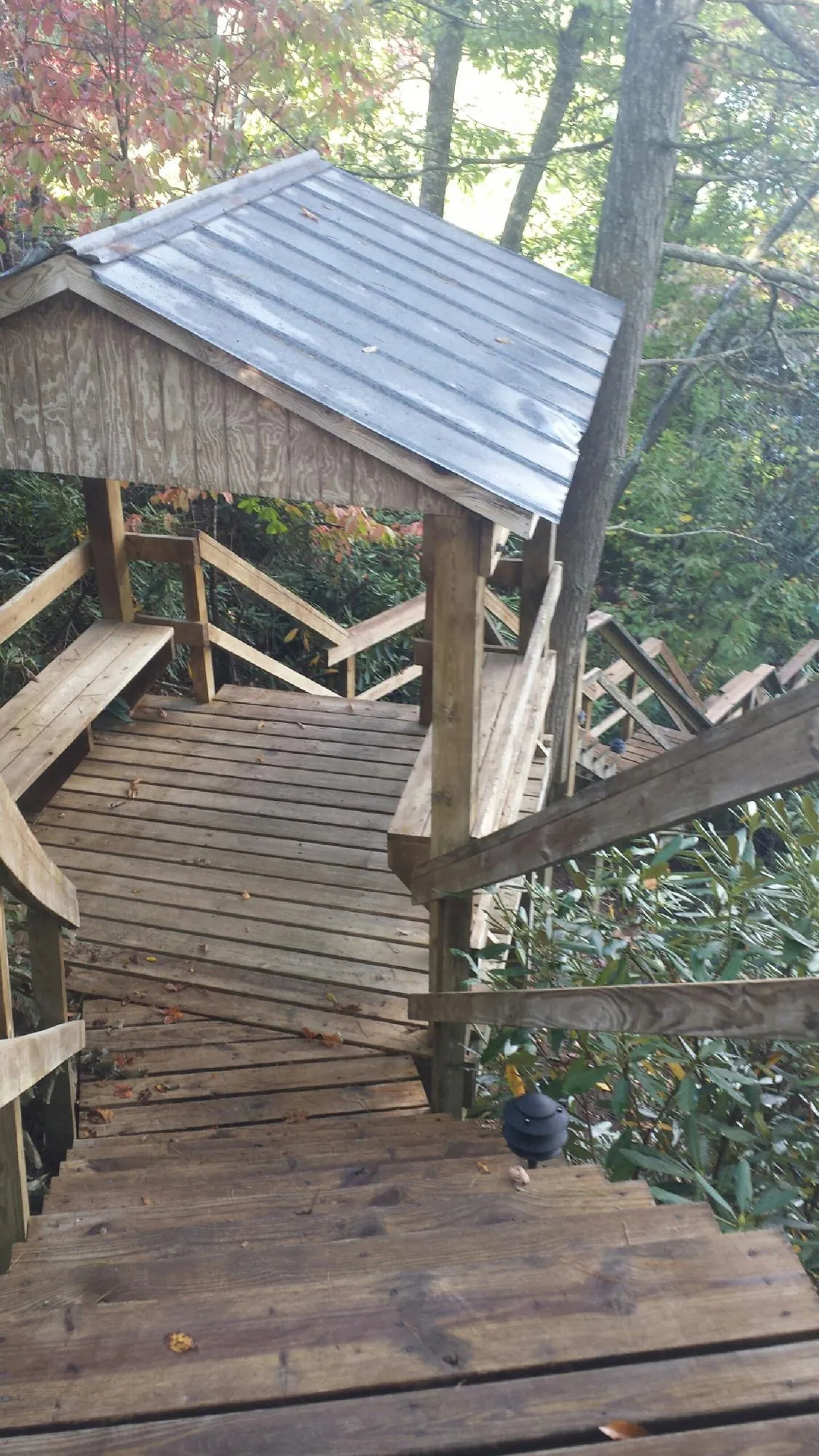 Metal roofed shelter over wooden steps on a wooded walkway — Skylight Repair & Installation work by our crew in Glen Hope