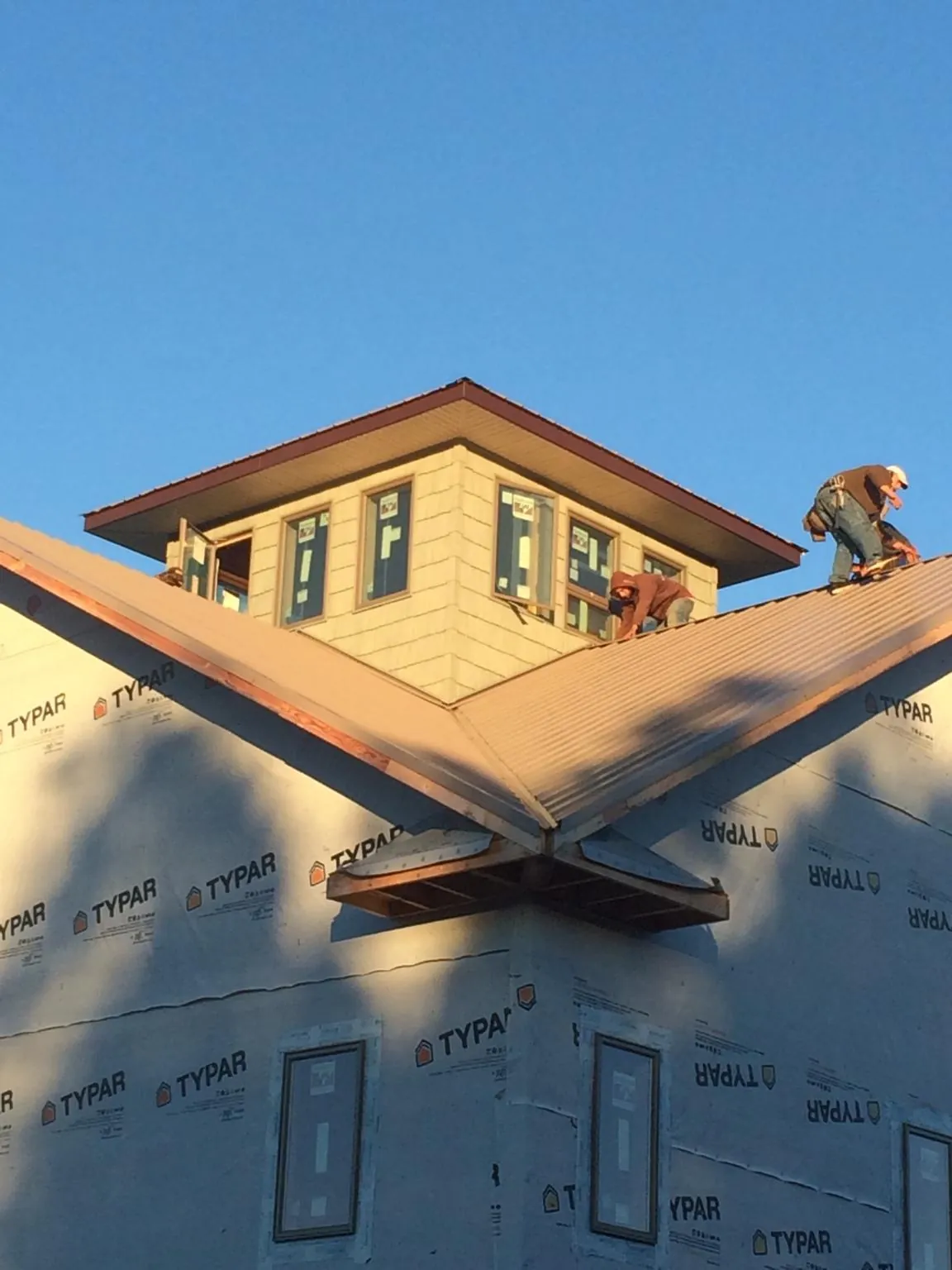 Roofers working around a rooftop cupola on a new metal roof at sunset — Roof Waterproofing in Glen Hope by Roofing Brothers